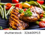 Grilled chicken breast in different variations with cherry tomatoes, green French beans, garlic, herbs, cut lemon on a teflon pan.