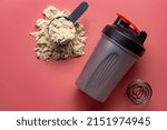Shaker and protein powder on pink background. Sports nutrition concept