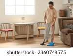Small photo of Man with broom sweeping floor at home