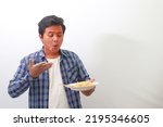 Portrait of shocked Asian man in plaid shirt eating spicy noodle and turning his face become red. Isolated image on white background