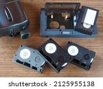 Small photo of Mini compact videocassettes, videocassette adapter, video camera on a wooden table, flat layout, closeup. Retro technology of the 90s, vintage