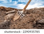 Small photo of Dirty shovel in fresh soil at a construction site in a pit. Deep hole in the ground. Earthworks, manual refinement of the soil. Dig deep ditches and holes