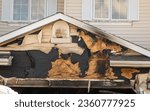 Small photo of A close-up view of a neighborhood garage roof, which bears the scars of recent accidental fire damage, expertly extinguished by firefighters in the midst of a tranquil autumn.