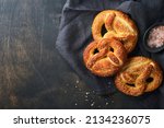 Small photo of Bavarian pretzels and glass of lager beer. Oktoberfest food menu, traditional salted pretzels over old dark wooden background. Top view with space for text. Oktoberfest theme