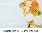 Small photo of Set or assortment cheeses. Maasdam, smoked cheese, camembert, blue cheese, parmesan, brie cheese with basil and pepper on on white marble board white wooden old background. Top view. Free copy space.