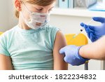 Small photo of Little girl in face mask in doctor's office is vaccinated. Syringe with vaccine for covid-19 coronavirus,flu,dangerous infectious diseases. Injection after clinical trials for human, child. Medicine.