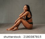 Lovely smiling African American female sitting and showing her well toned body