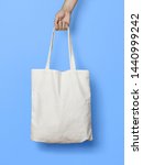 Small photo of Hand Holding Fabric Canvas Tote Bag or Goodie Bag Isolated on White Colour Background