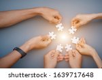 Small photo of The hand of a businessman holding a paper jigsaw And solve the puzzle together. The business team assembled a jigsaw puzzle. A business group wishing to bring together the puzzle pieces