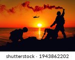 Silhouette of army special forces infantry soldiers, Marines or Navy SEALS team signaling to helicopter with smoke flair while waiting for evacuation, landing on seashore during amphibious operation