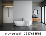 Small photo of Modern bathroom interior with blue and white tones wall, concrete floor, wooden vanity with black sink and oval mirror, white bathtub, panoramic windows.