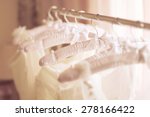 Beautiful white cream wedding dresses made of silk chiffon, tulle and lace hanging on hangers with bows 