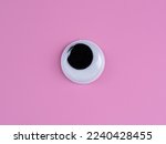 single wobbly googly eye isolated on a pink  background with copyspace business logo