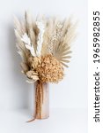 Small photo of Dried flower arrangement in a pink vase. Including Banksia, Hydrangea, pampas grass, Palm Fronds, cream Ruscus leaves, and rust Amaranthus. Photographed on a white background.