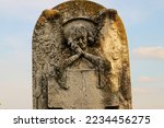 Small photo of An atique tombstone with a praying angel. The writings from the tombstone have obliterated by time.