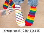 Small photo of Child legs wearing mismatched pair of striped socks. Odd Socks Day, Lonely Sock Day. Anti-Bullying Week.