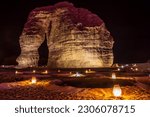 Small photo of Illuminated outdoor lounge in front of elephant rock erosion monolith standing in the night desert, Al Ula, Saudi Arabia