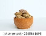 Baked groundnut, Goober or Monkey Nut, or Arachis hypogaea, in a wooden bowl. Isolated on white background