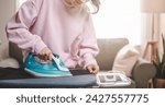 Small photo of clothes, appliance, home, housework, iron, ironing, laundry, steam, clean, domestic. close-up young woman's hand using electric steam, water vapor from iron press pile shirt clothes on an ironing.
