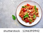 Penne pasta with tomato in red sauce on a white plate over light grey slate, stone or concrete background.Top view with copy space.