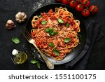 Traditional italian spaghetti bolognese on a black plate on a dark slate, stone or concrete background. Top view with copy space.