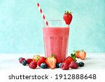Fresh cold strawberry berry smoothie in a tall glass on a light blue slate, stone or concrete background.