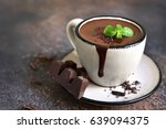 Portion of homemade mint hot chocolate in a cup on a dark slate,stone or metal background.