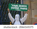 Small photo of Albi, France - October 2, 2021 - "To live happy, stay fearful" : on opponent to the health passport, anti lockdown protester, disguised with a masquerade mask and white blouse, brandishes a placard