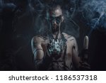 Small photo of Dark tribal shaman or warlock summoning spirits using a deer skull and his ritual staff, halloween concept
