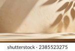 Small photo of Empty table against beige textured wall background. Composition with glossy leaves on the wall.