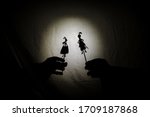 Chinese shadow theater for children projected on a bed sheet, themed of Saint George. The shadows are of cardboard, you can see the hand that manipulates them. dragon, tales, storyteller, princess