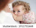Small photo of Extended breastfeeding an older baby beyond infancy; close-up portrait of 2-3 years old toddler with curly hair. Color photo.