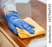 Small photo of Woman wiping table countertop in kitchen by wet cloth rag. Female charwoman hand cleaning disinfect office home restaurant surfaces. Close up.