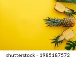 Small photo of Pineapples and palm leaves on yellow color summer background. Whole tropical summer pineapples fruits and sliced pineapple halves flat lay composition with copy space