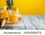 Tasty pineapple juice in glass with ingredients on white wooden table with yellow summer background. Fresh natural pineapple juice cocktail and juice Glass with copy space