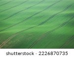 Close-up, abstract detail of tractor track lines over the rolling countryside landscape in the farmland of South Moravia in the Czech Republic.