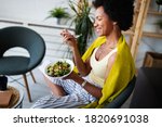 Beautiful afro american woman eating vegetable salad at home.