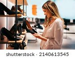 Portrait of beautiful young woman shopping new shoes in store. People shopping concept.