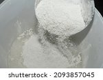 Small photo of Close-up of the mixture in a bucket of powder putty for wall finishing, putty or glaze. Building materials concept. Dry plaster powder topcoat. Selective focus