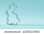 Easter bunny on blue background. Happy Easter Day concept. Minimal Easter concept. Space for text. Easter Cookie Cutter on baking background.