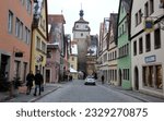 Small photo of Rothenburg ob der Tauber, Germany - February 6, 2023: Galgengasse, Gallows Alley, medieval street in the old town, view toward White Tower, on the winter afternoon