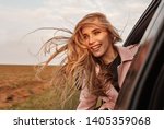 Happy young smilling woman enjoying nature traveling in a car and looking out.