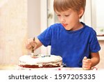 Small photo of Little kid boy decorating cake and smacks his lips. Cooking children at home kitchen, happy sweet childhood, people making tasty appetite food