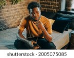 Small photo of Black young man listening to music otr telecoference on mobile phone. Technologies and online social media