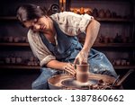 Small photo of Charming handicraftsman shows how to work with clay and pottery wheel. Making ceramic dishes.