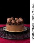 Small photo of Ferrero rocher chocolate cake on plate on black placemat and black background