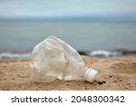 Crumpled plastic bottle on the sandy beach against the background of the sea Day Recycling