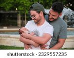 Gay happy couple with their newborn baby in a park. Four days old infant, parenthood concept.