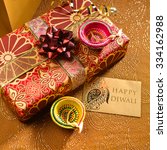 Small photo of 'Happy Diwali' message on a tag along with gift box and lamps. Indian festive background.