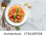 Pasta with cherry tomatoes, cheese and basil on a light background. High key, top view, copy space